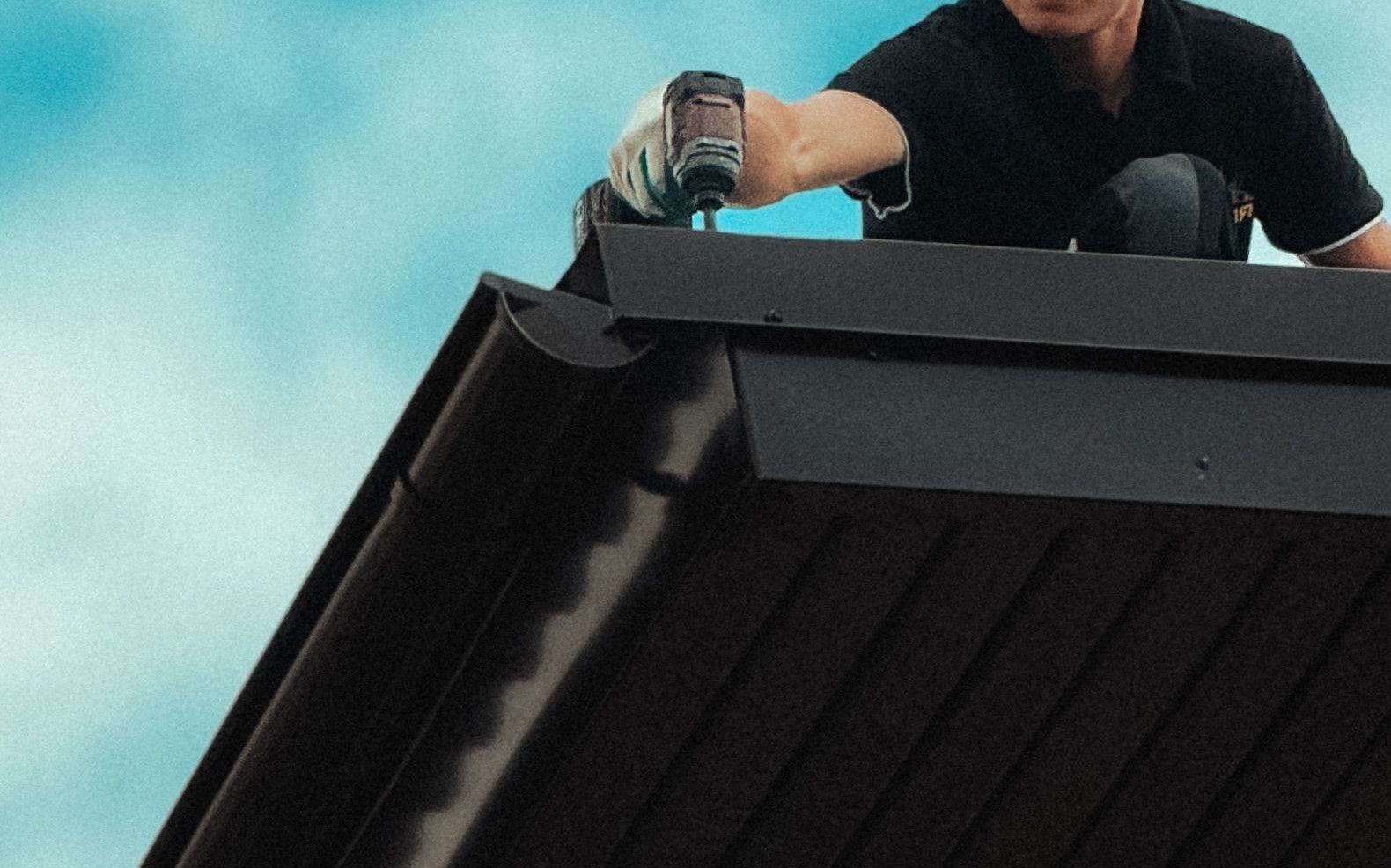 Roofer working diligently on a house roof under a bright blue sky. Professional roofing maintenance in progress.